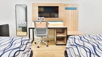 A hotel room with two beds, a desk, a chair, a mirror, and a TV.