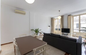 A living room with a sofa, a dining table, chairs, a TV, and a large window with curtains. - Your Sunny Home in Málaga (Málaga)