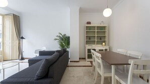 Un salon moderne comprenant un canapé, une table à manger, des chaises, une plante et une bibliothèque.