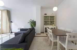 A modern living room with a sofa, dining table, chairs, a plant, and a bookshelf. - Your Sunny Home in Málaga (Málaga)