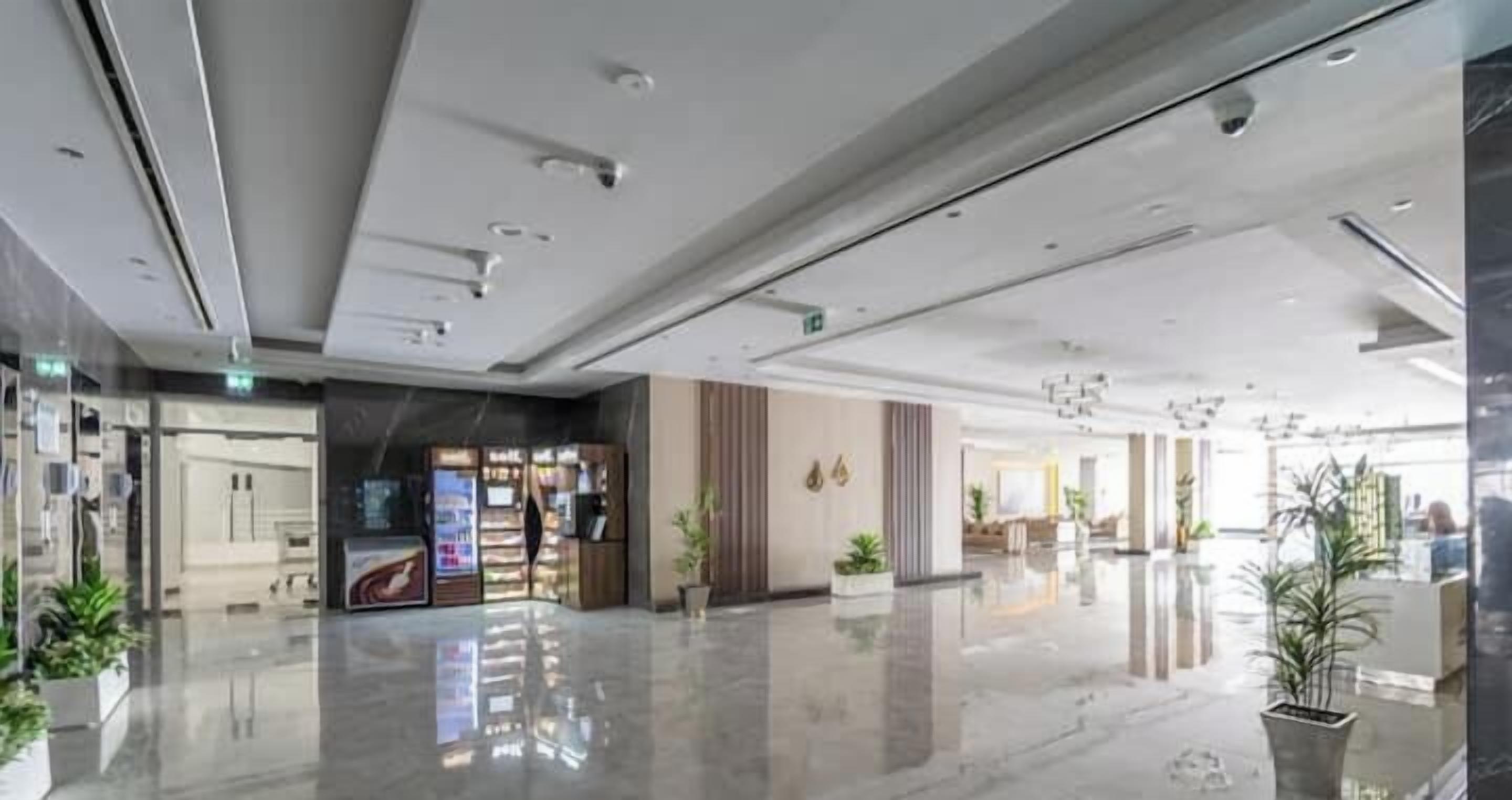 Eine geräumige Lobby mit glänzendem Boden, Verkaufsautomaten und Blumentöpfen.