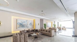 A spacious lobby with a modern sofa set, a glass coffee table, and a large abstract painting. - Vogue | Hera Tower Sports City near First Avenue Mall (Dubai)