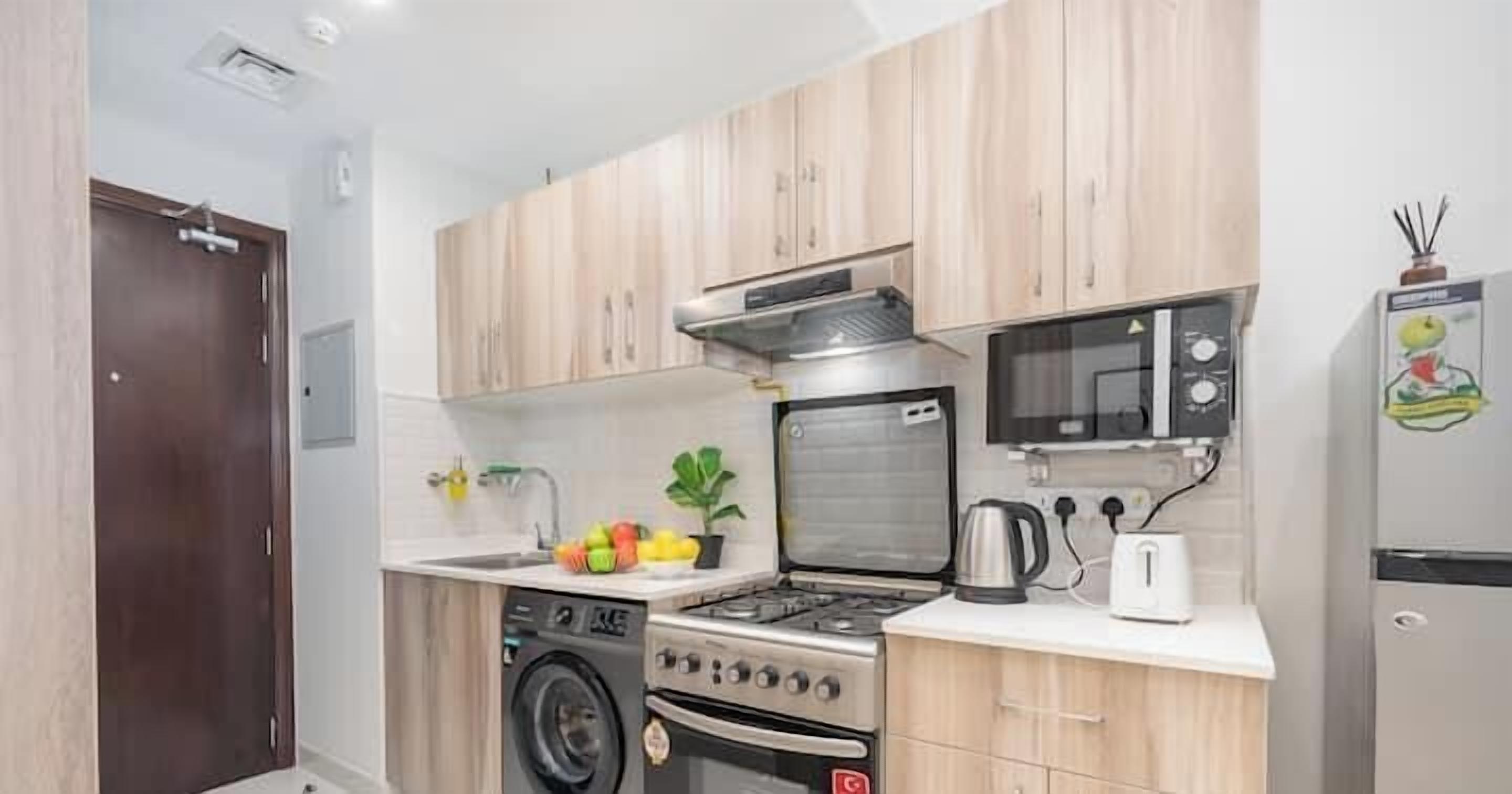 Cozinha compacta com armários de madeira, forno embutido, micro-ondas e geladeira.