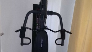 Un vélo d’appartement est installé dans une pièce aux murs blancs et au sol carrelé.
