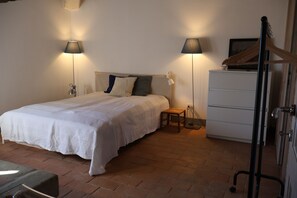 A bedroom with a bed, bedside lamps, a wooden bench, a dresser, and a coat rack. - Secluded Chianti Estate with Infinity Pool in the Hills of Siena (Toscana)