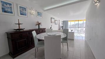 Un comedor con una mesa redonda, sillas, un armario de madera y cuadros en la pared.