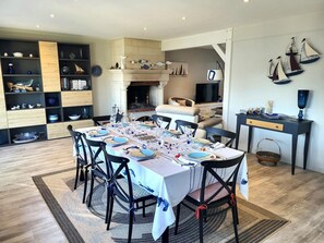 A dining area with a table set for six, surrounded by chairs, a fireplace, and a television.