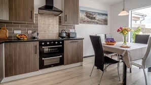A modern kitchen with wooden cabinets, a built-in oven, and a dining area with a table and chairs.