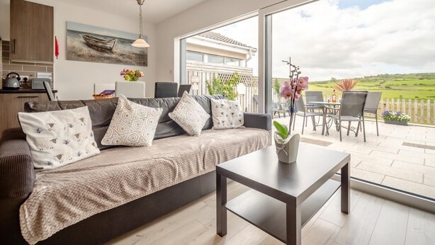 A modern living room with a sofa, coffee table, and a view of the outdoors.