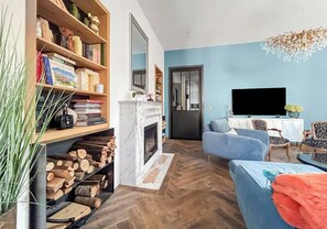 Un salon avec une cheminée, un téléviseur et un canapé bleu.