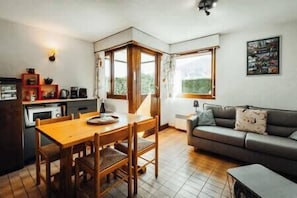 A compact living space with a dining area, kitchenette, and a sofa. - Mountain views and tennis at Megève's gates (Demi-Quartier)