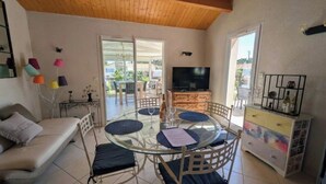 Ein Wohnzimmer mit Glastisch, Sofa, Fernseher und Balkonblick.