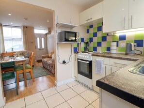 A compact kitchen with a stove, microwave, and tiled backsplash. - Hill View (Bala)