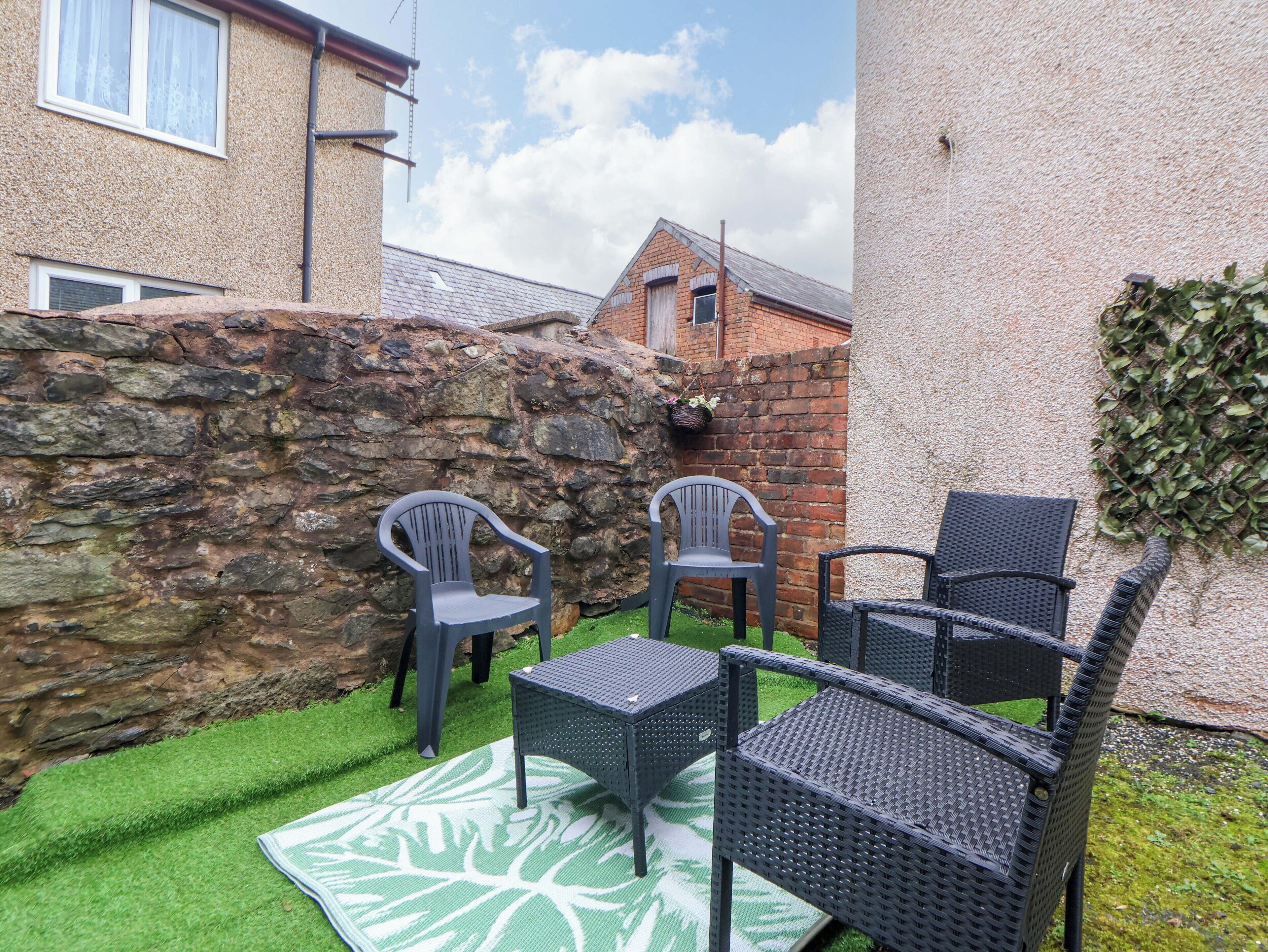 A patio with outdoor furniture, a stone wall, and a grassy area.