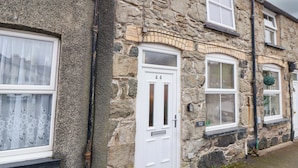 A stone building with a white door marked '44', windows with shutters, and a small sign indicating 'Jill View Cottage'.