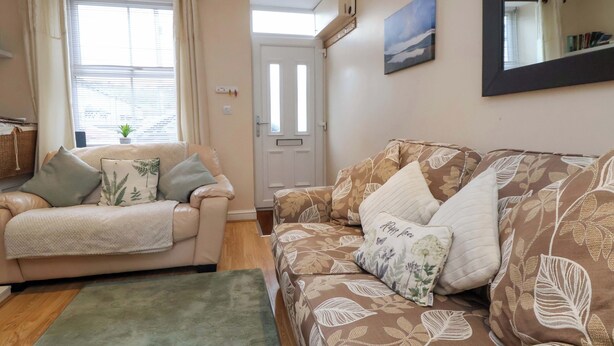 A living room with a sofa, a chair, a rug, a door, and a wall-mounted mirror.
