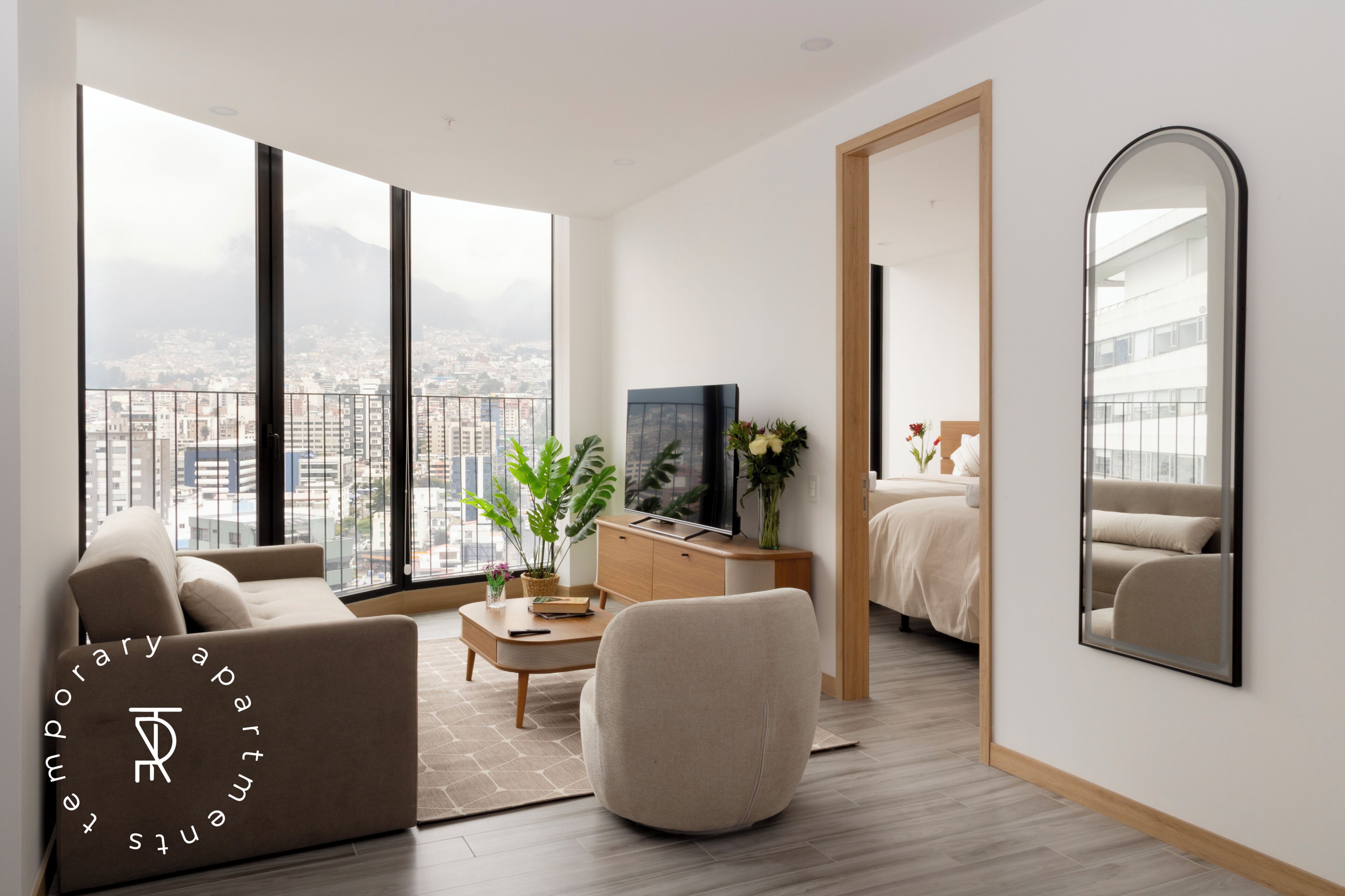 Un salon moderne avec une grande fenêtre, un canapé, une table basse, un téléviseur et un lit.