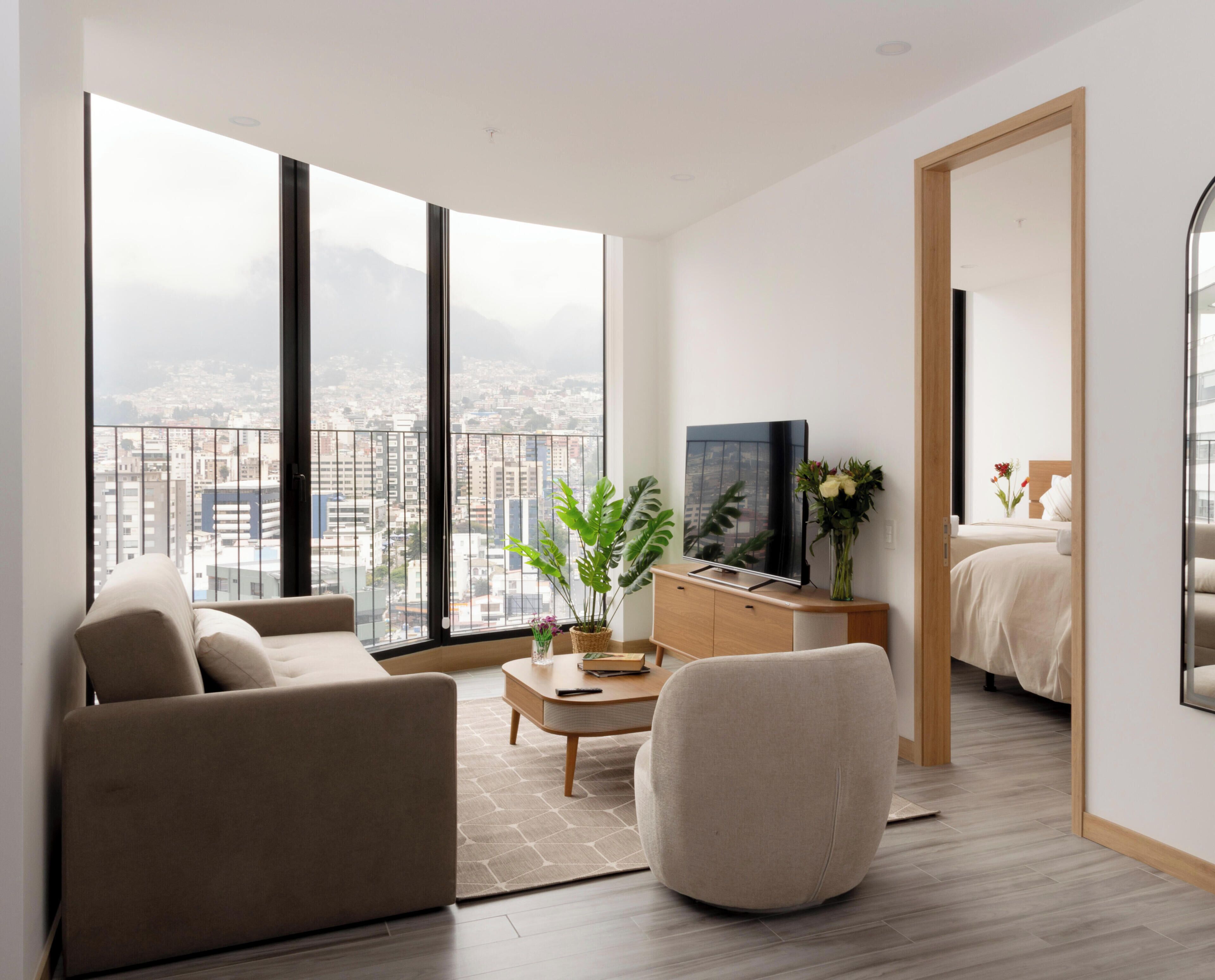 Una sala moderna con sofá, sillón, mesa de centro y televisor.