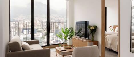 Una sala moderna con sofá, sillón, mesa de centro y televisor.