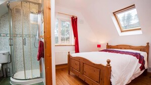 Una camera da letto con un letto di legno, una finestra vista, una doccia con porta in vetro e una tenda rossa.