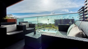Un espace extérieur moderne, aménagé avec une balustrade en verre, une piscine et une vue sur la mer.