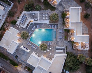 Vista aérea de un resort con piscina, tumbonas y un área de estar techada.