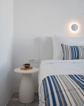 Un dormitorio con una cama, una mesita de noche con un cuenco y una lámpara de pared.