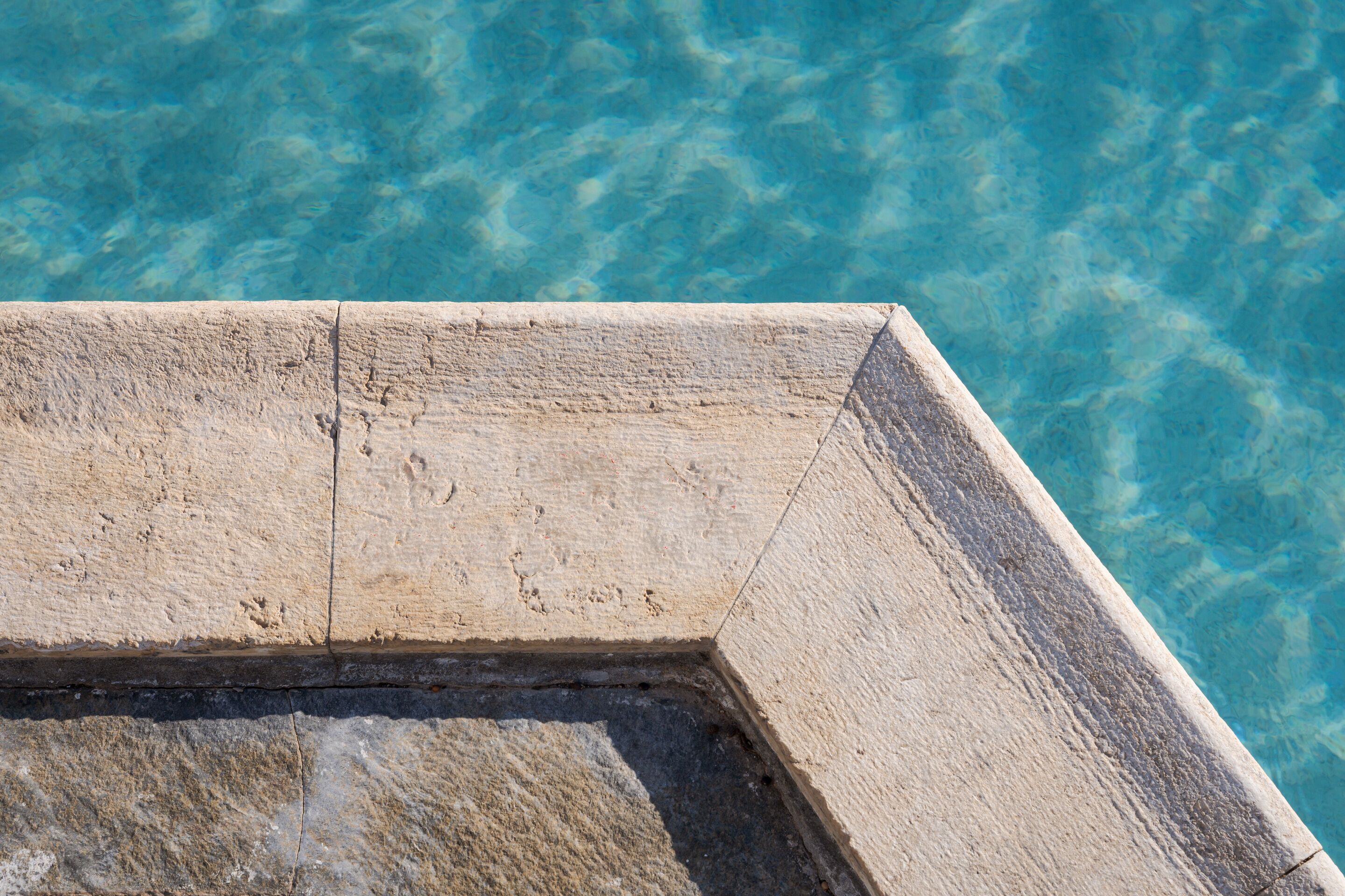 Un saliente de piedra con una piscina de agua cristalina al fondo.