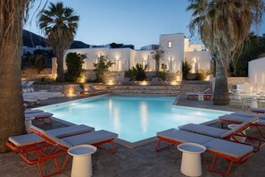 Zona de piscina con sillones de descanso y pared de piedra.