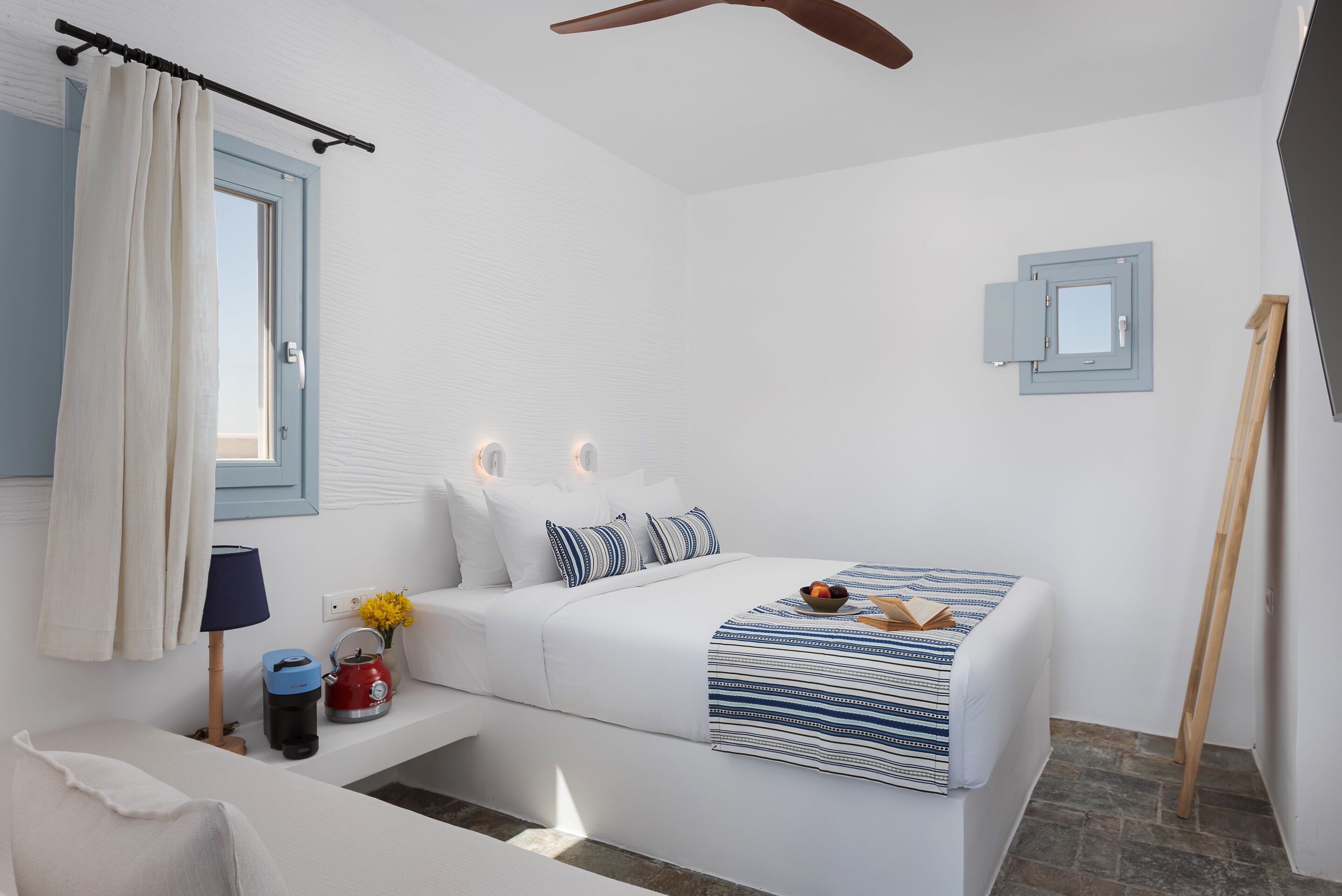 Un dormitorio con cama, mesita de noche, lámpara y ventana con cortinas.