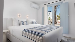 Une chambre d’hôtel moderne avec un grand lit, une petite table de chevet, une fenêtre avec des rideaux et un appareil de climatisation fixé au mur.