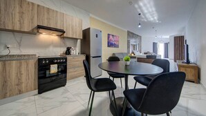 Une cuisine moderne équipée d’un four encastré, d’un réfrigérateur et d’un coin repas avec une table ronde et des chaises.