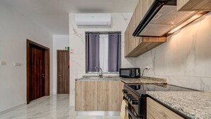 Une cuisine équipée d’un four à micro-ondes, d’un four et d’un évier intégrés, de placards en bois et d’un sol en marbre.