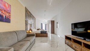 Une chambre d’hôtel moderne avec un grand lit, un canapé, une télévision et un sol en marbre.