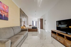 A modern hotel room with a large bed, a sofa, a TV, and a marble floor. - Premium Tarxien Studio w/ Balcony Retreat (Tarxien)