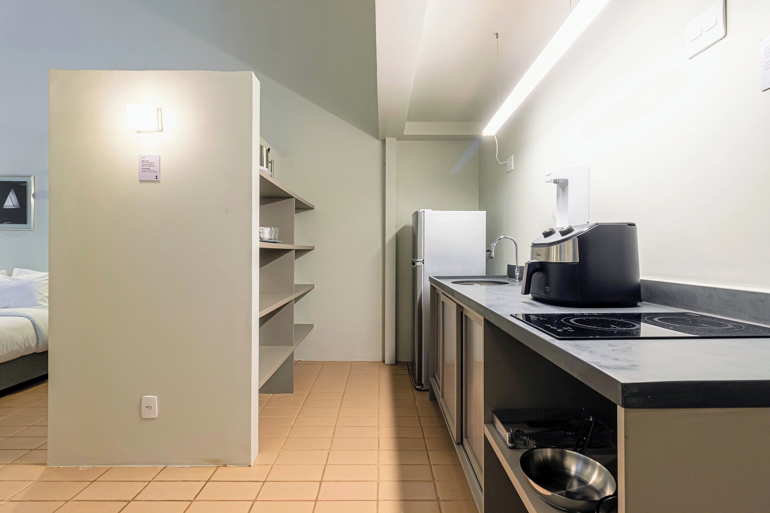 A modern kitchen with a built-in stove, a refrigerator, and a coffee maker.