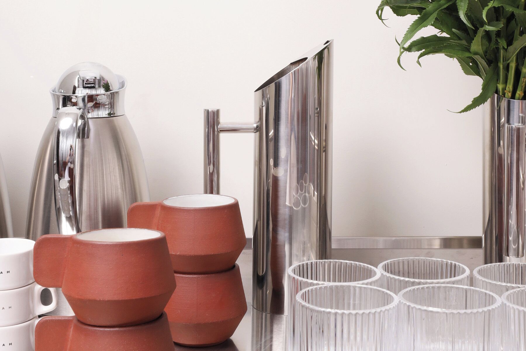 Une cuisine équipée d’appareils électroménagers en acier inoxydable, avec des tasses en terre cuite et une plante en pot.