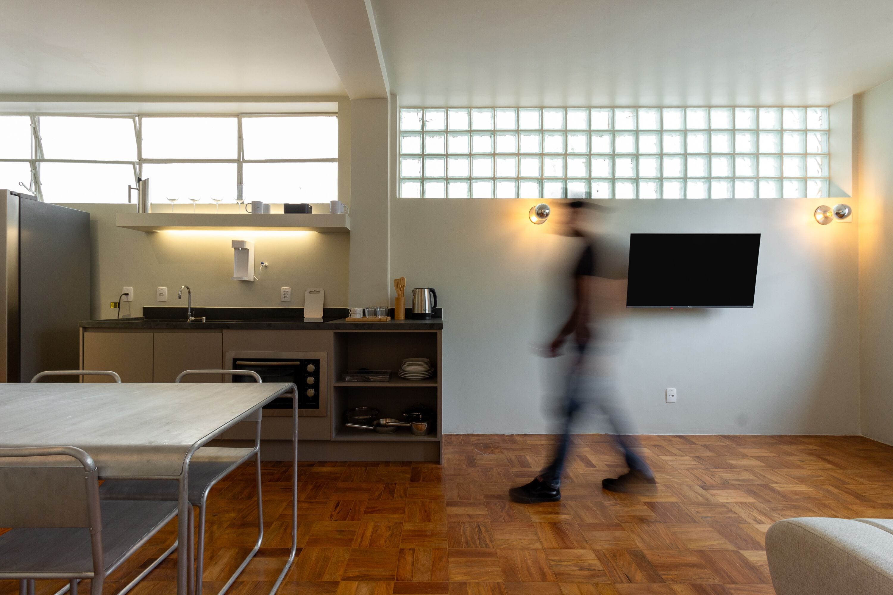 Una cocina moderna con comedor, televisor montado en la pared y un ventanal grande.