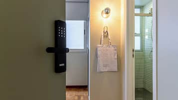 A hallway with a door lock, a wall-mounted light, a bag, and a glimpse of a bathroom.