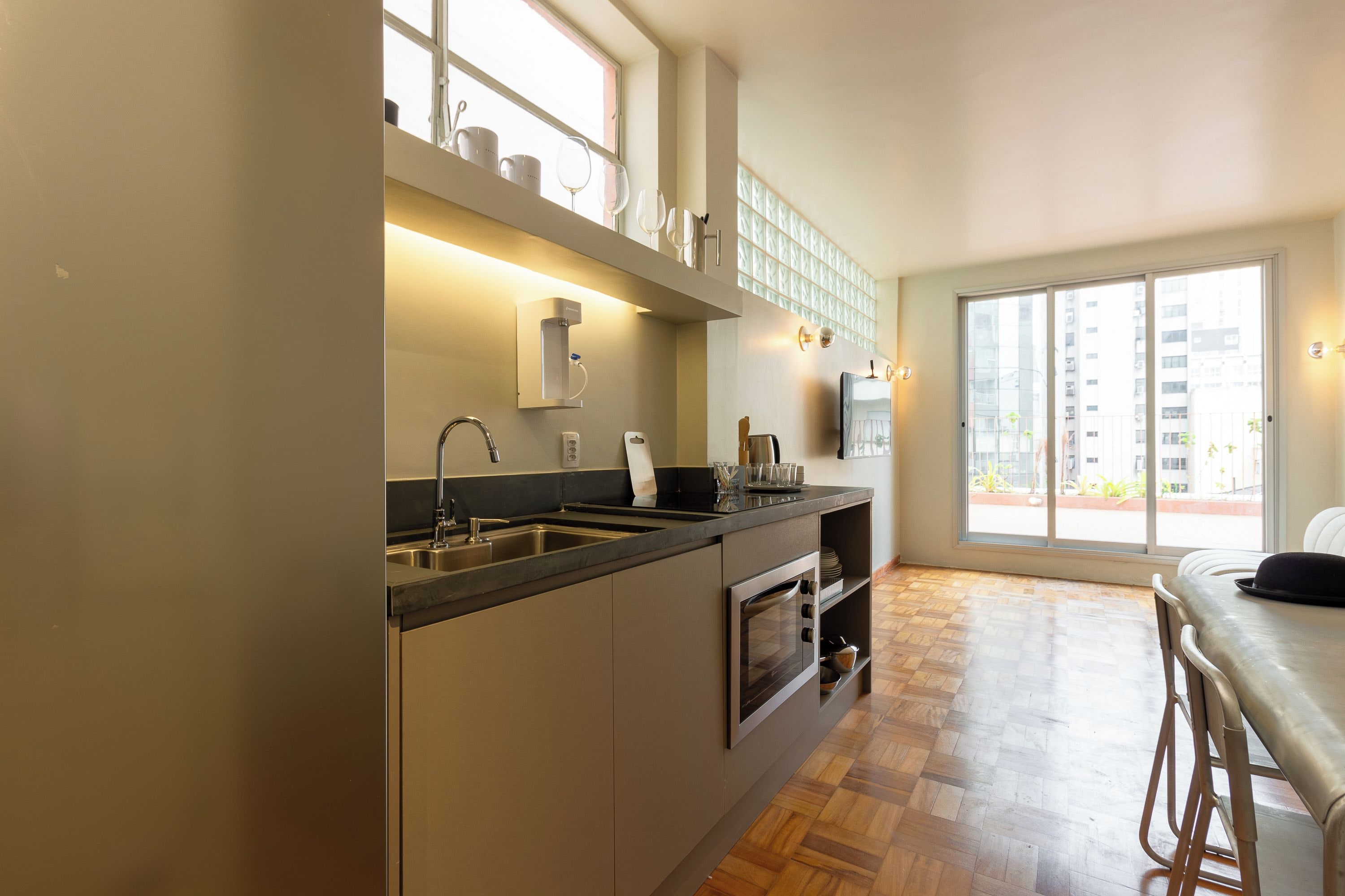 A modern kitchen with a built-in oven, a sink, and a window overlooking a cityscape.