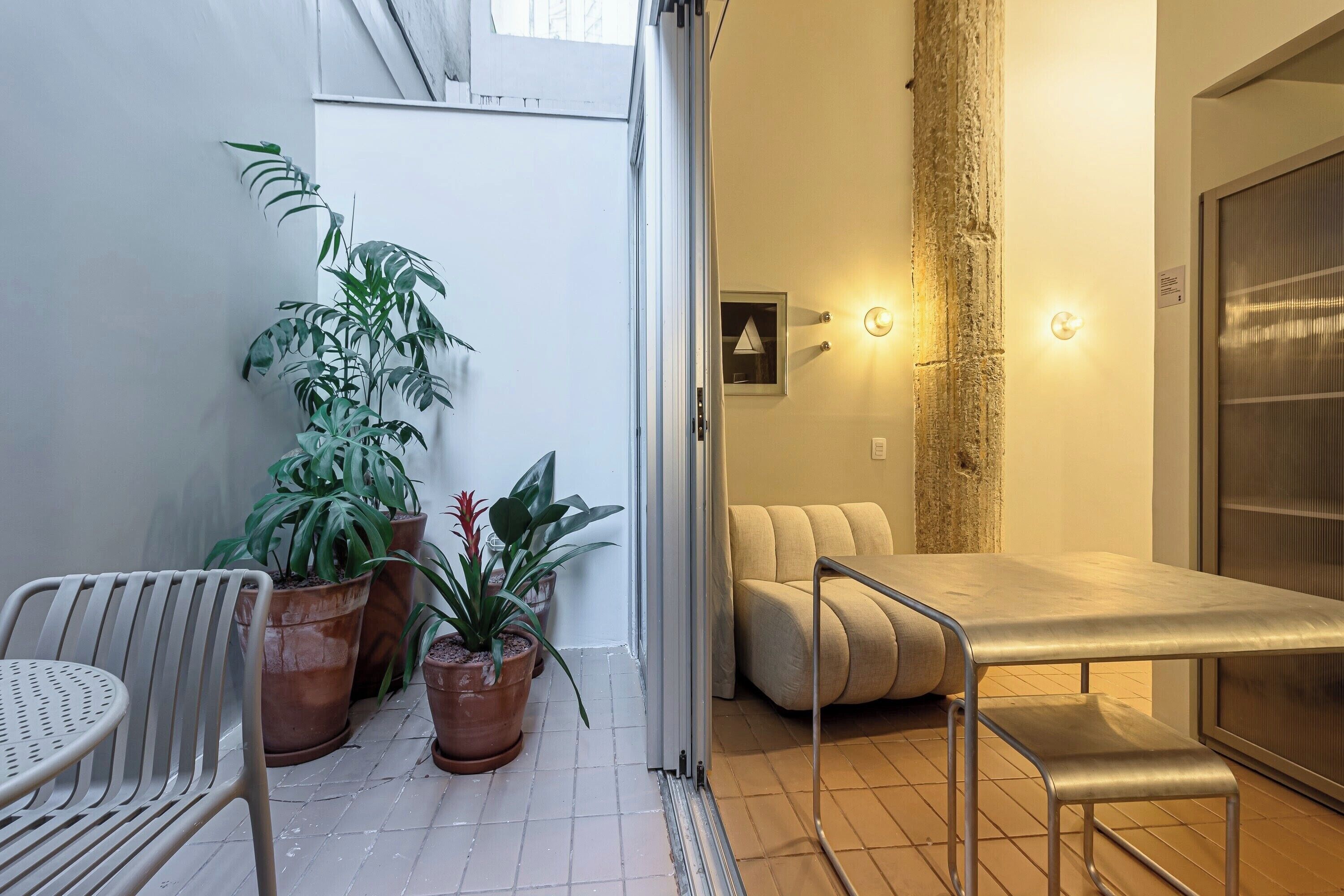 Une pièce moderne avec un canapé, une petite table et des plantes en pot.