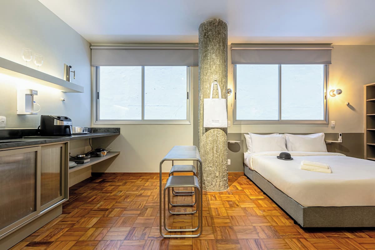 Hotelkamer met een bed, een bureau, een stoel, een grote pilaar en een raam.