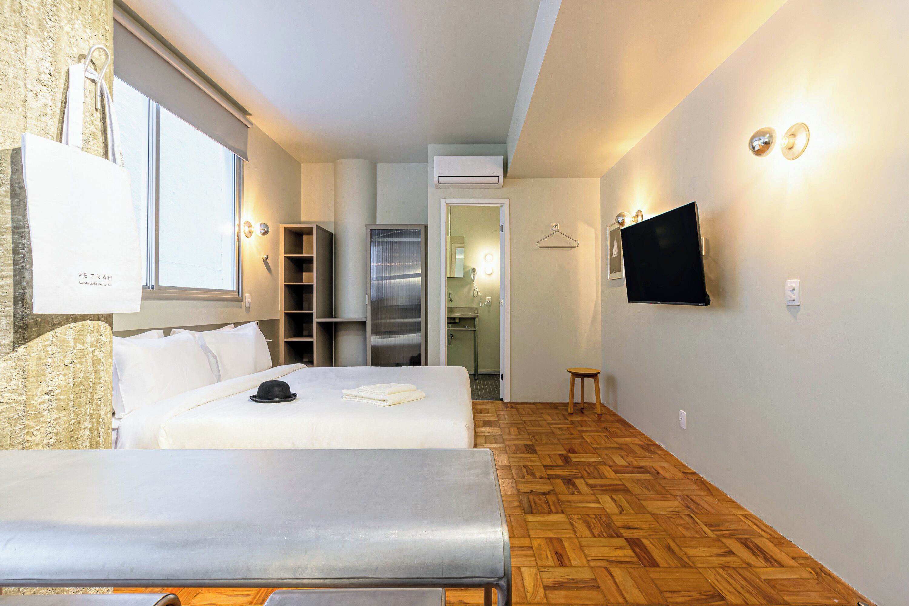 A hotel room with two beds, a TV, a wardrobe, and a kitchenette.