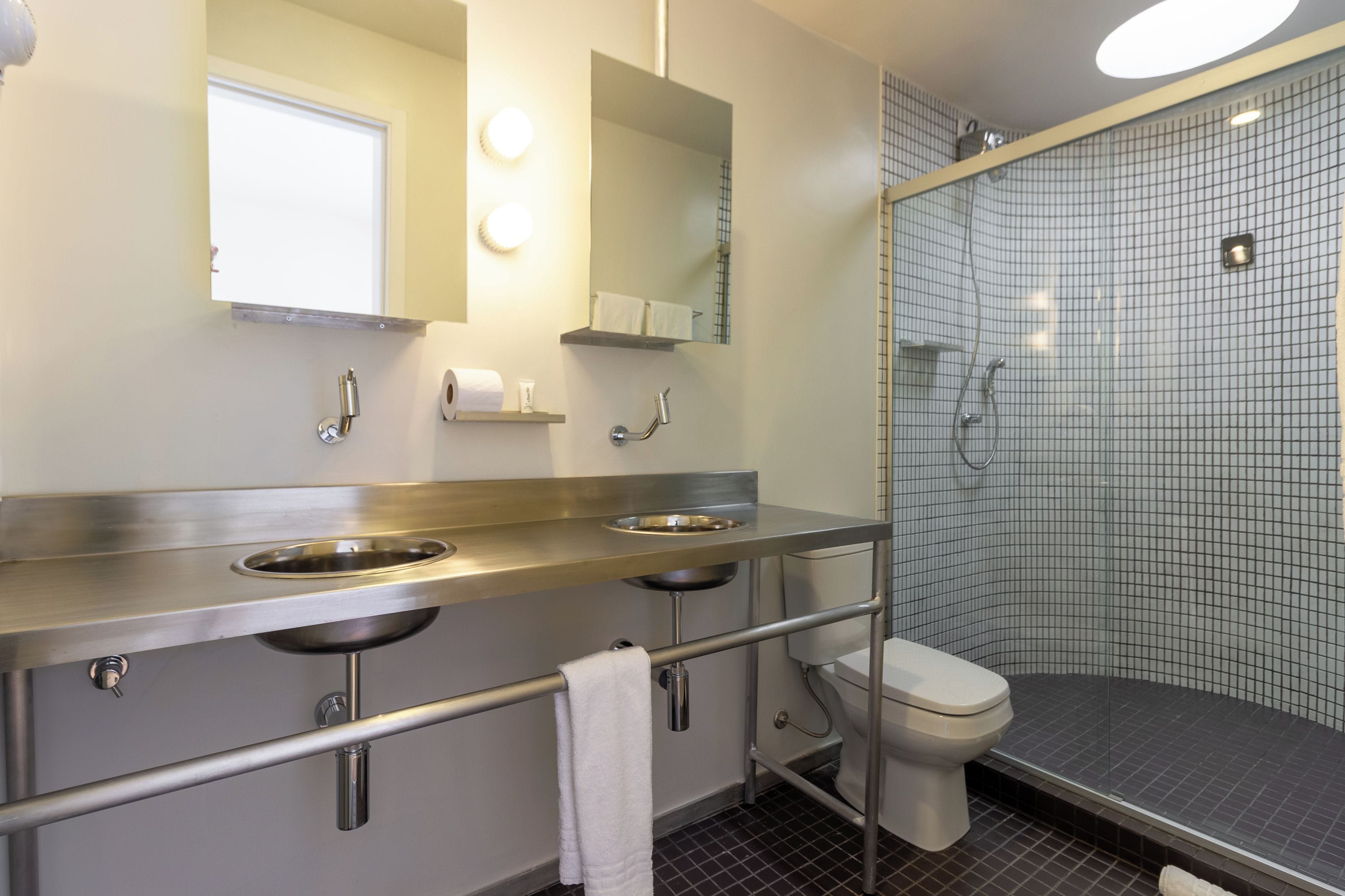 A modern bathroom with two sinks, a toilet, and a shower.