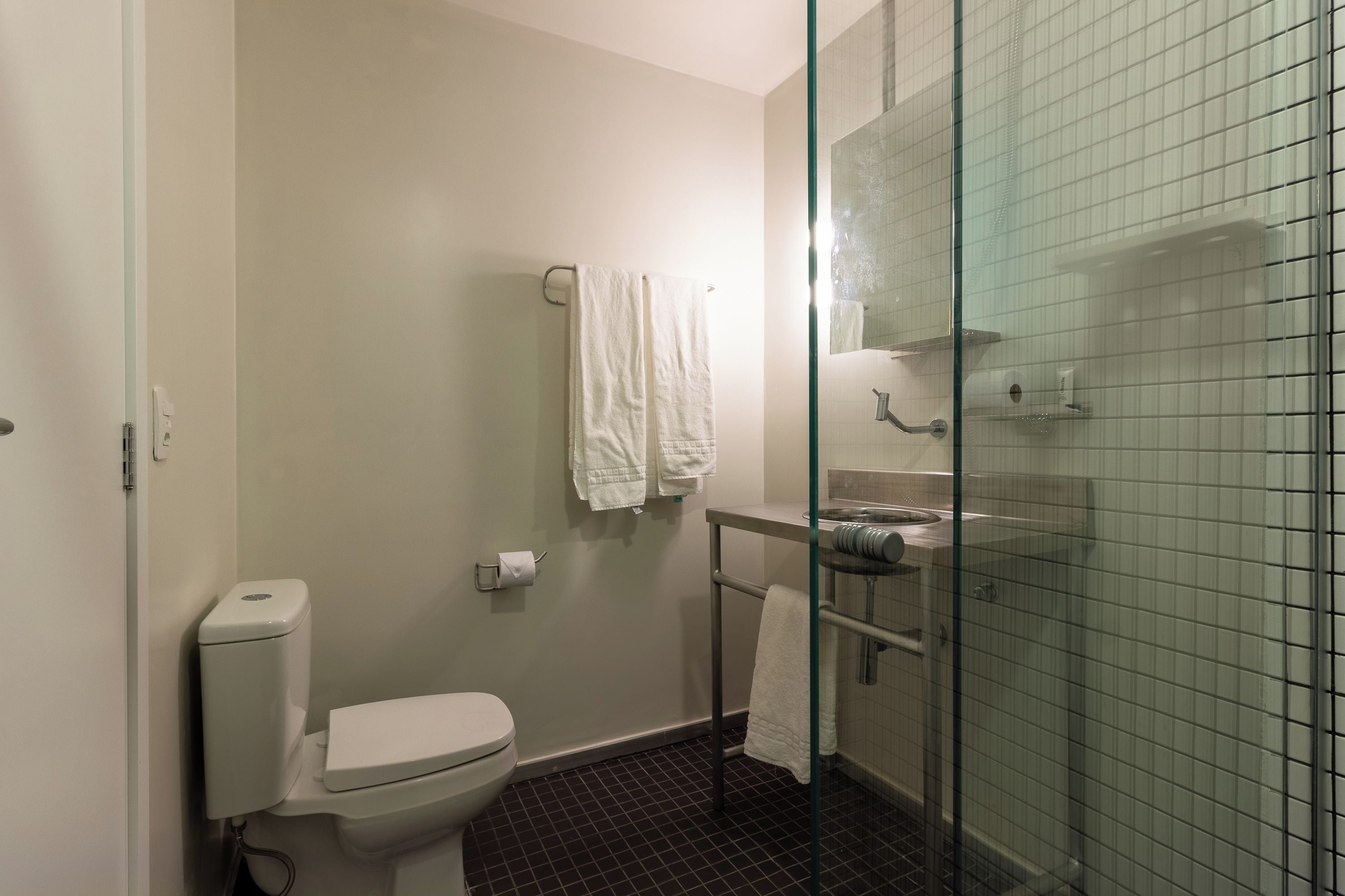 A bathroom with a toilet, a glass shower enclosure, and a sink.