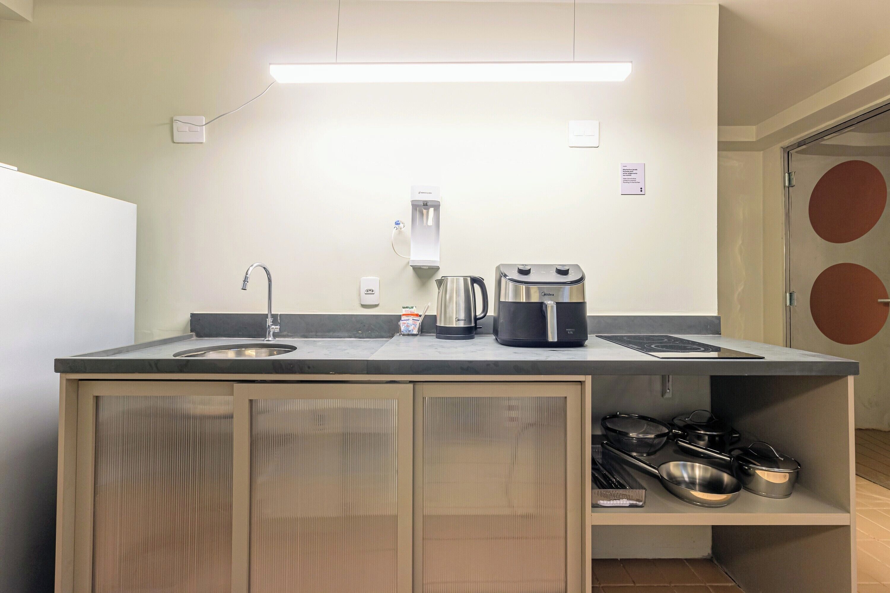 A compact kitchen with a sink, kettle, toaster, and a coffee machine.
