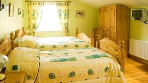 A bedroom with two wooden beds, a wooden wardrobe, a television, and a window with curtains. - 2 Bed in Ballybay (oc-ii04618) (Ballybay)