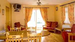 A room with a wooden dining table, chairs, a sofa, a television, and curtains. - 2 Bed in Ballybay (oc-ii04618) (Ballybay)