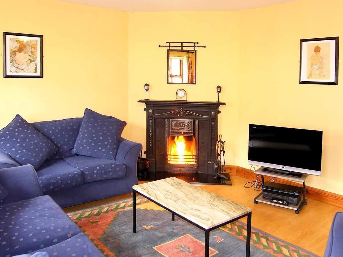 A living room with a sofa, a fireplace, a television, and artwork on the walls.