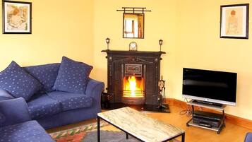 A living room with a sofa, a fireplace, a television, and artwork on the walls.